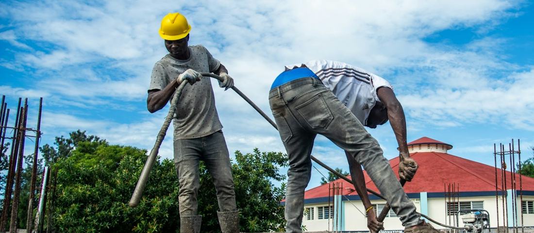 Concreters pouring and vibrating a slab over steel reinforcement
